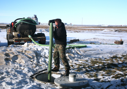 A man is pumping water into a manhole in the snow
