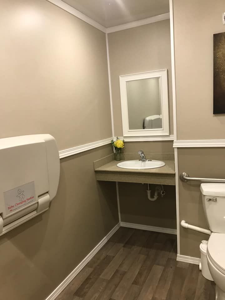 A bathroom with a toilet , sink , mirror and changing table.