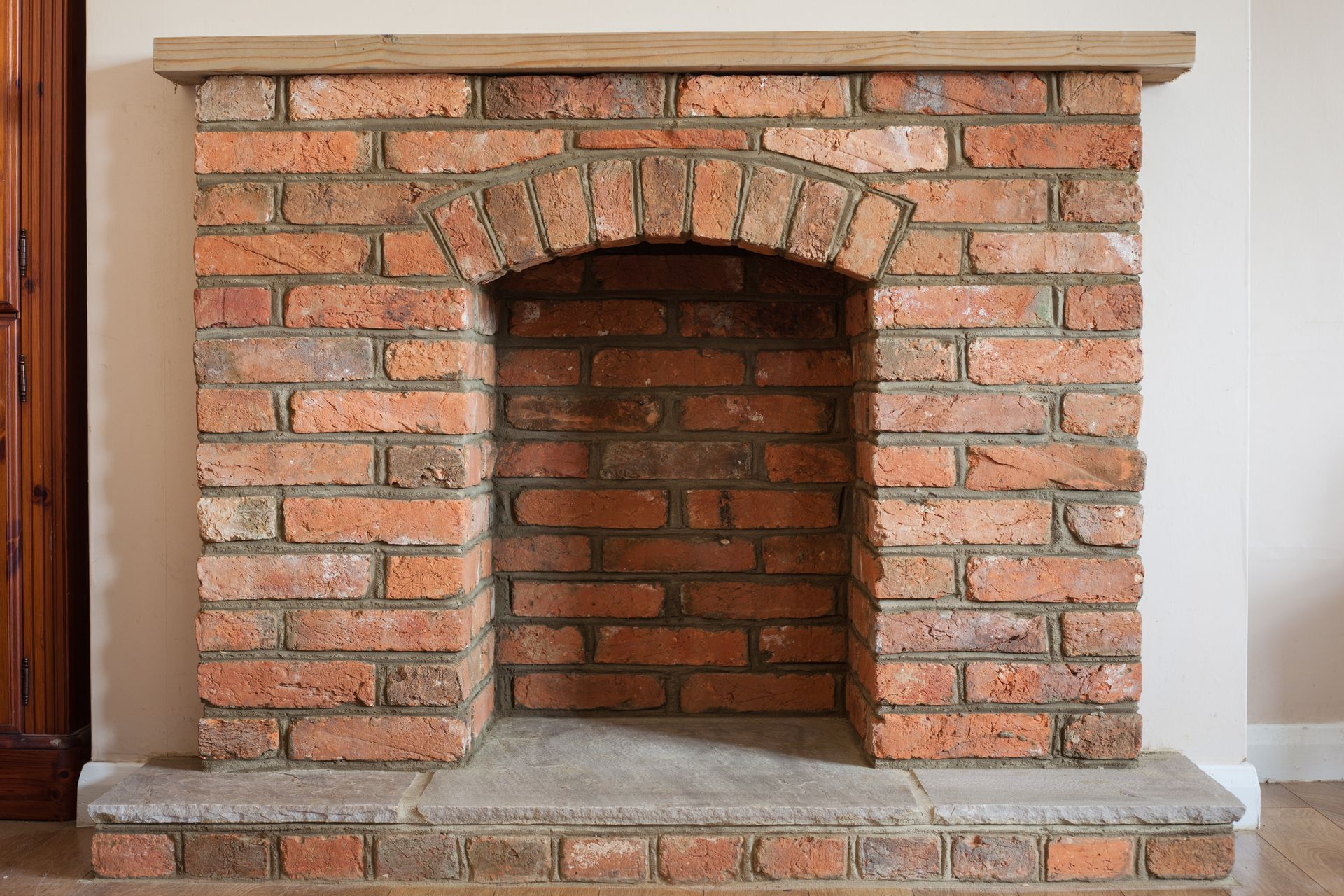 Brick fireplace with arched opening and stone mantel.