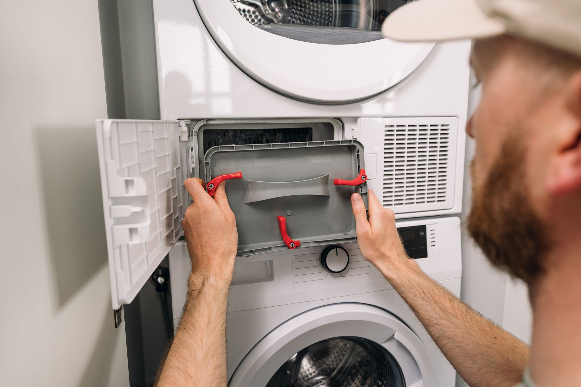 Person replacing a dryer lint filter in a laundry room. Person replacing a dryer lint filter in a laundry room.
