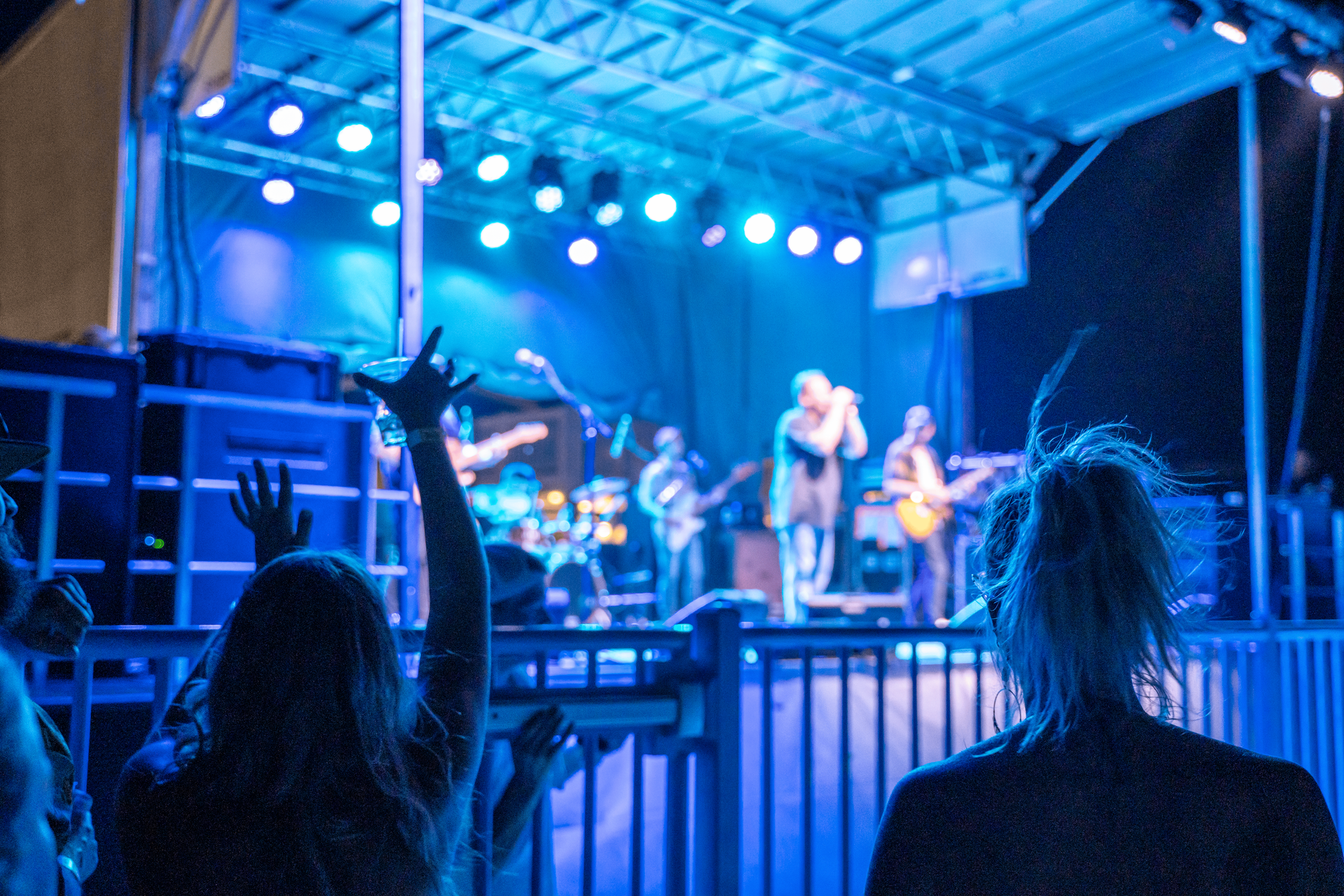 A group of people are standing in front of a stage with their hands in the air.