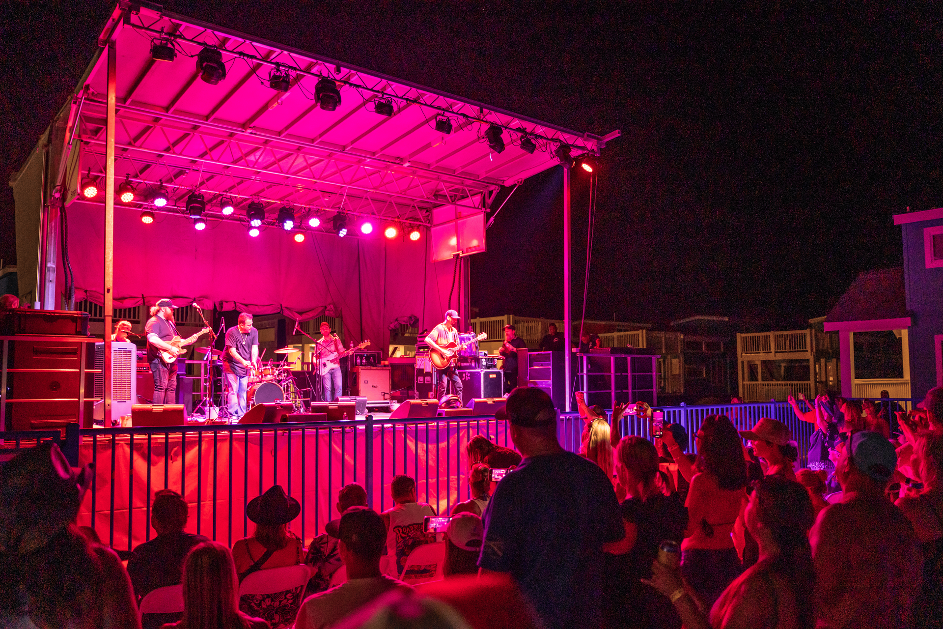 A group of people are sitting in front of a stage with purple lights.