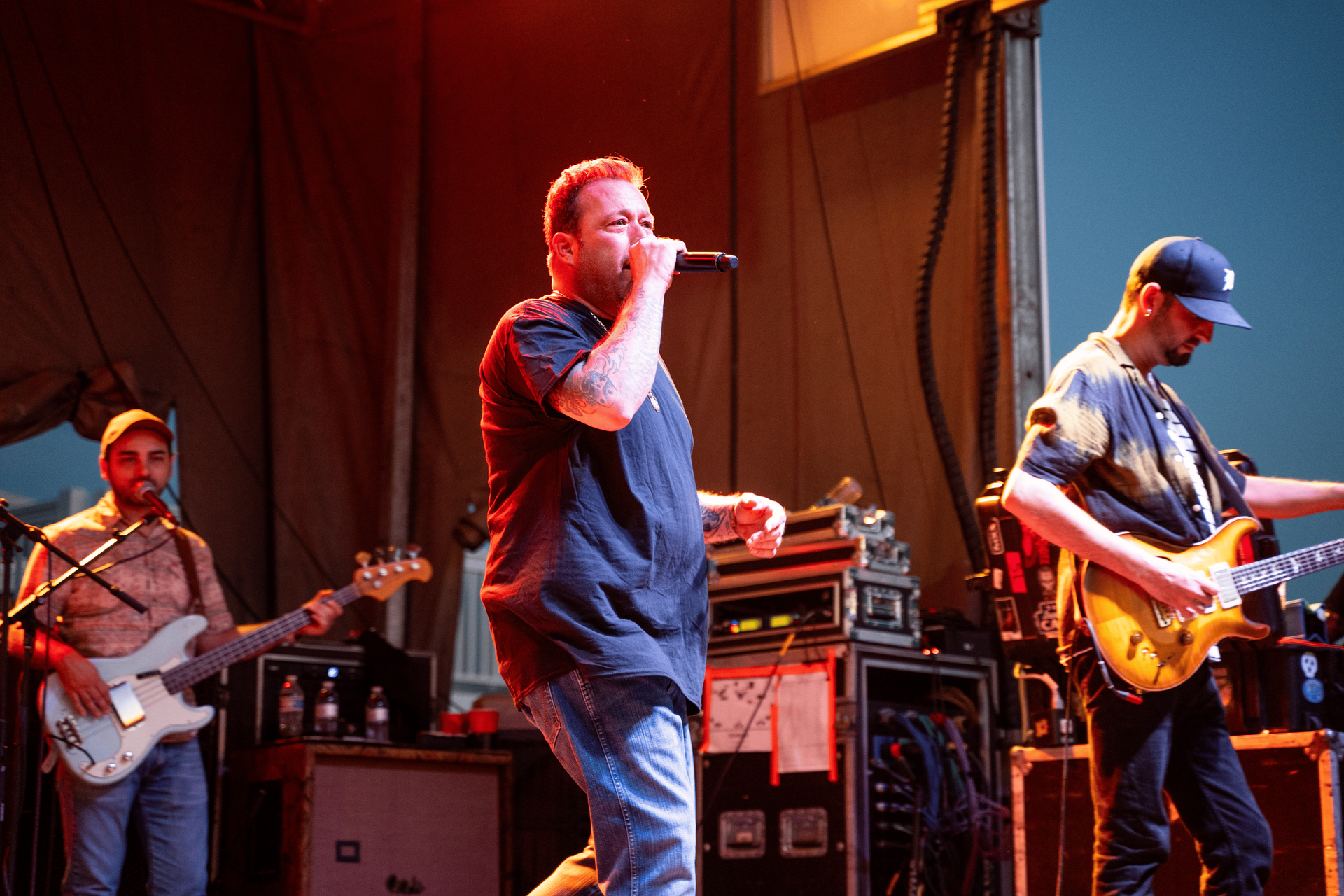 A man is singing into a microphone while two other men play guitars on stage.