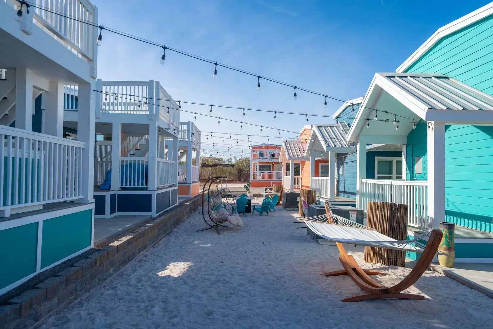 A row of small houses on a beach with a hammock in the middle.