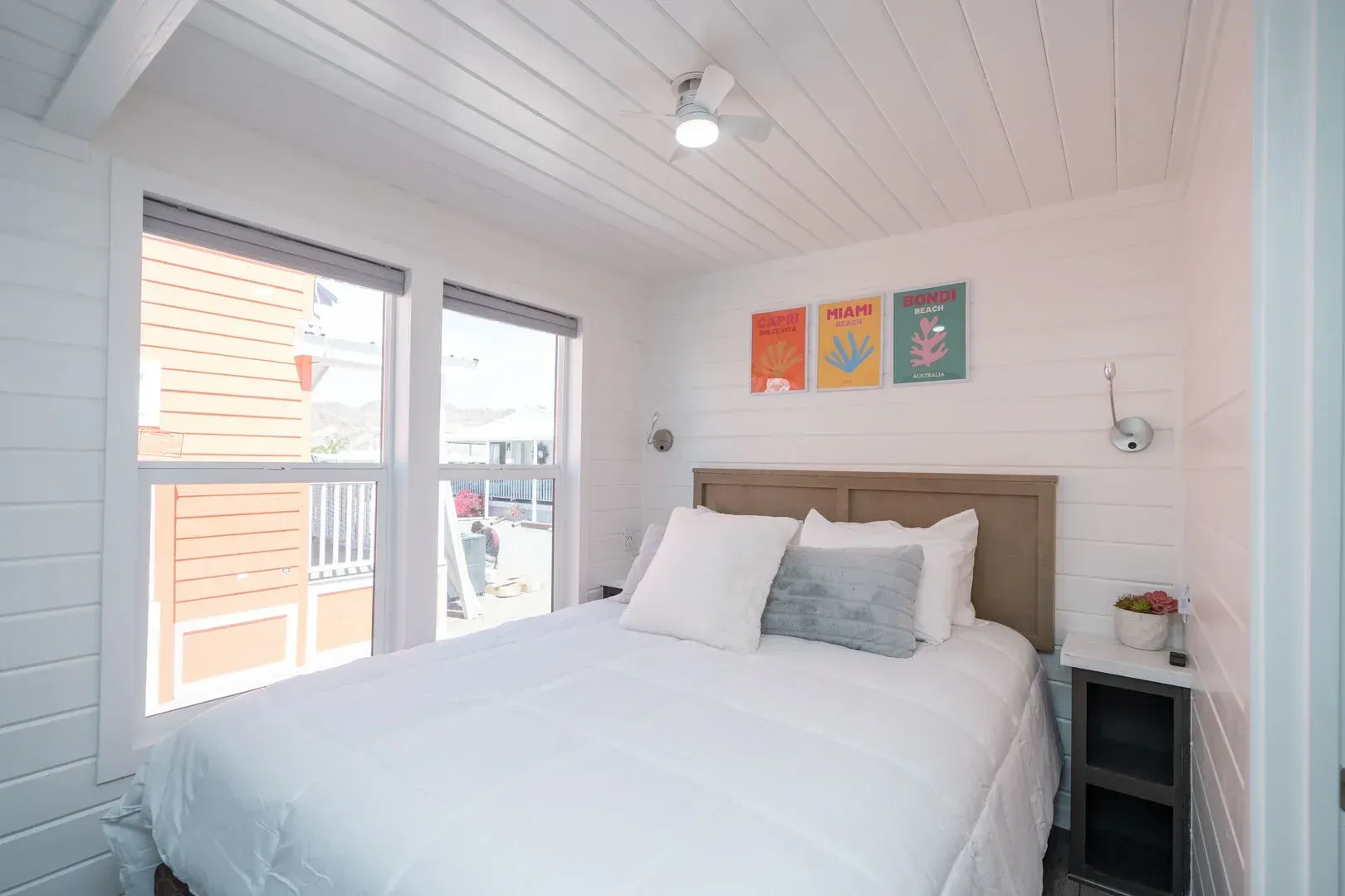 A bedroom with a bed , nightstand , and two windows.