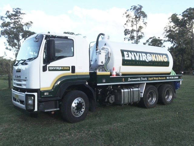 White and green Enviroking septic truck parked on grass.