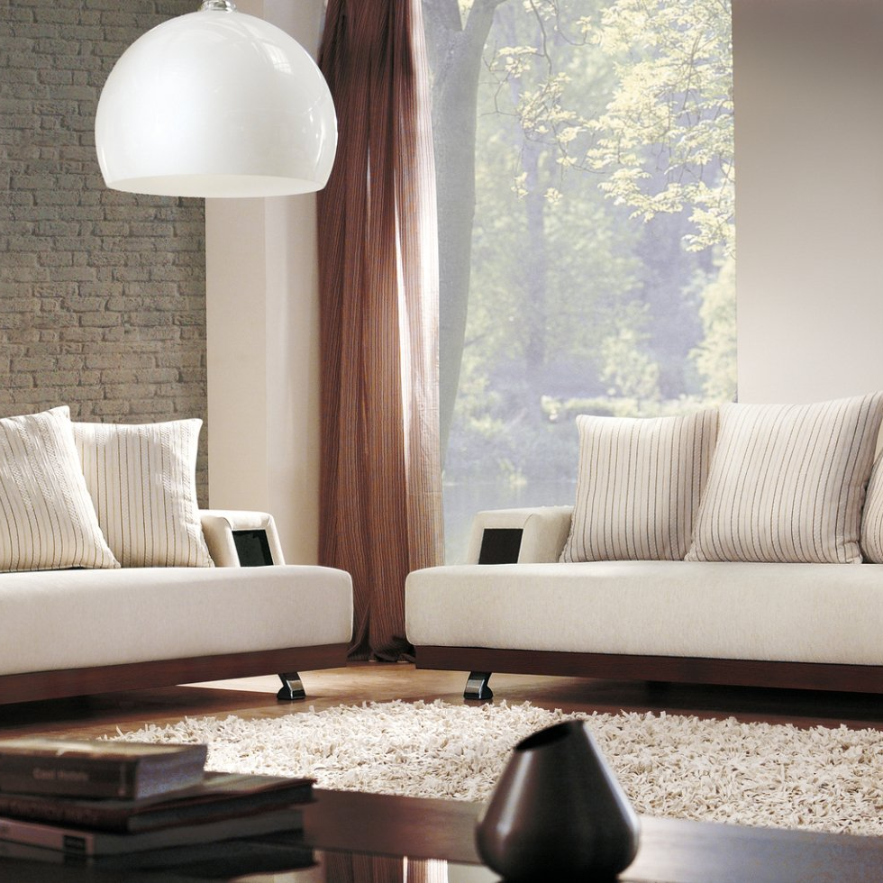 Living room with pink curtain pulled to the side, showing white sheers softening view of outdoor greenery. White comfy couches frame white shaggy rug, with decorated coffee table in foreground.