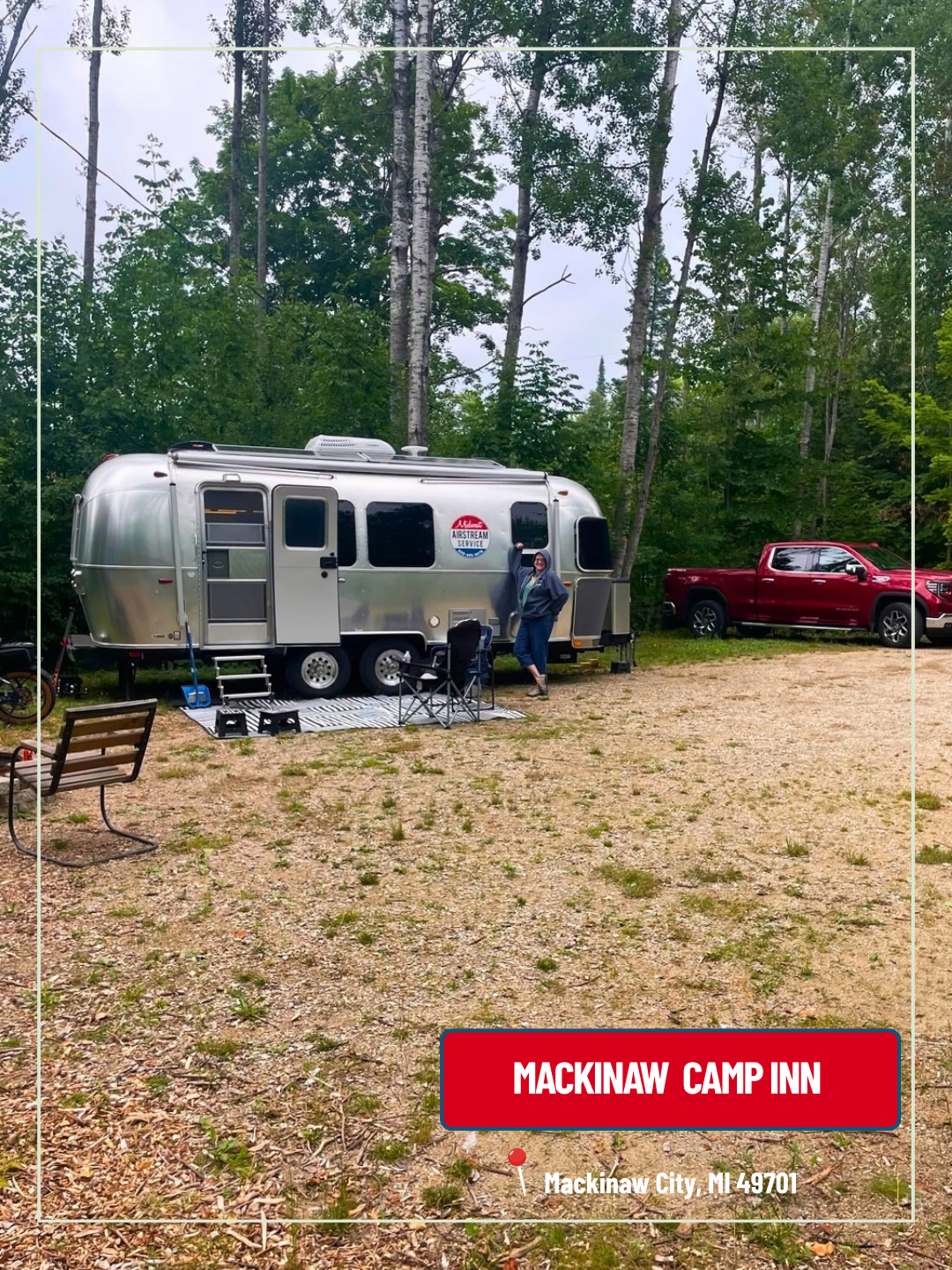 Silver Airstream trailer at a wooded campsite with a red pickup truck and camp gear