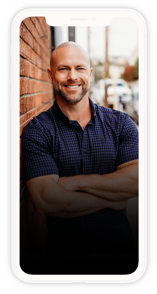 A man is standing in front of a brick wall with his arms crossed.