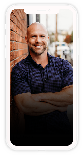 A man is standing in front of a brick wall with his arms crossed.