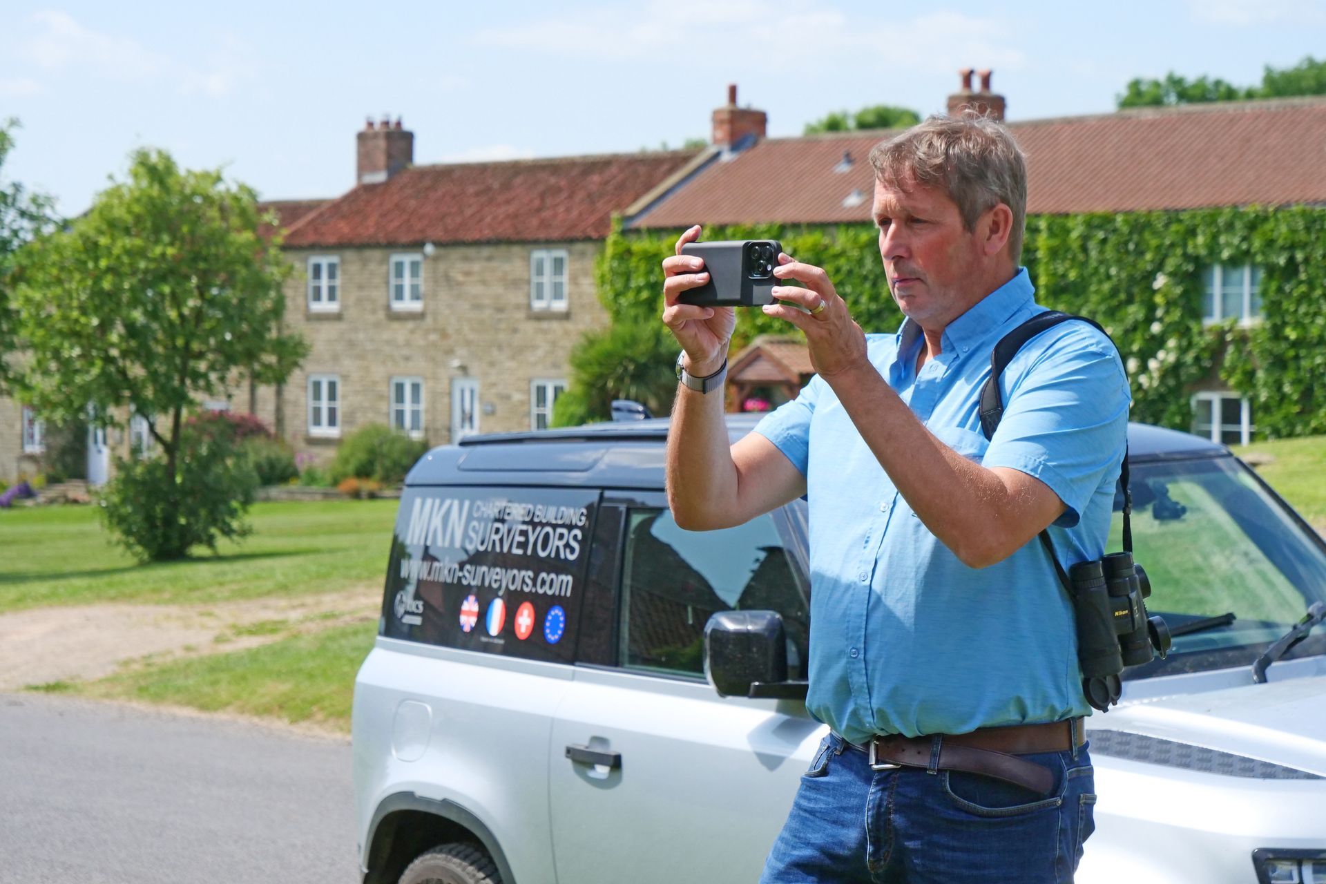 Man in a blue shirt taking a photo with a camera