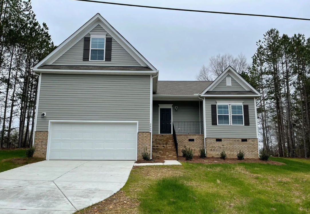 A house with a garage and a driveway in front of it.