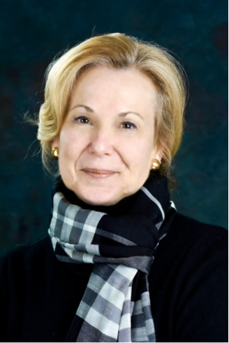 Portrait of a smiling person in a black top and striped scarf against a dark blue background