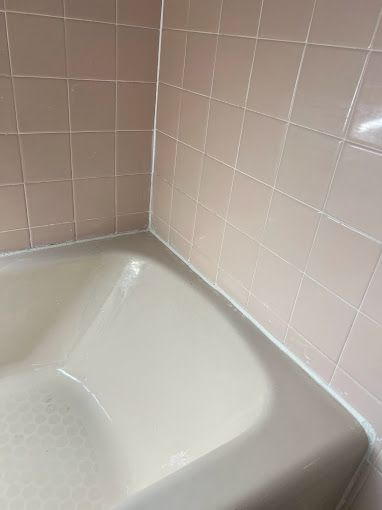 A white bathtub in a bathroom with pink tiles.