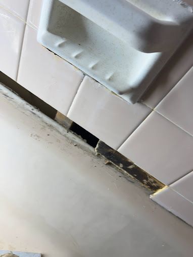 A bathroom with white tiles and a soap dish on the wall.