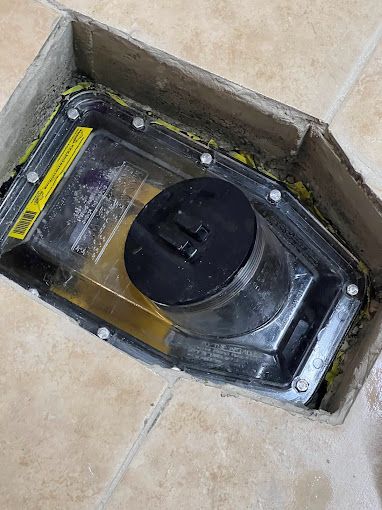 A vacuum cleaner is sitting in a cardboard box on a tiled floor.