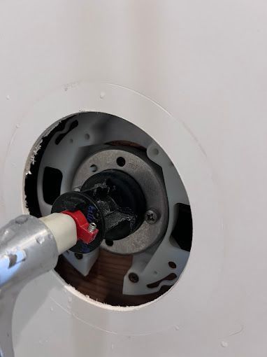 A close up of a hole in a wall with a hose coming out of it.