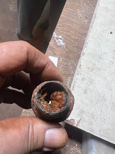 A person is holding a rusty metal object in their hand.
