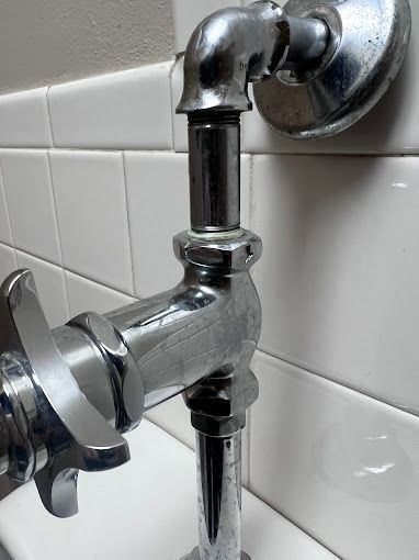 A close up of a toilet flush valve in a bathroom.