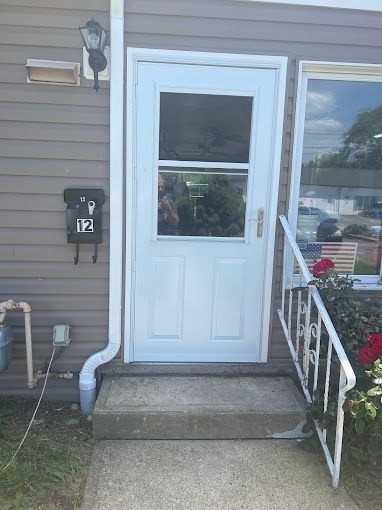 A white door with a window is on the side of a house.