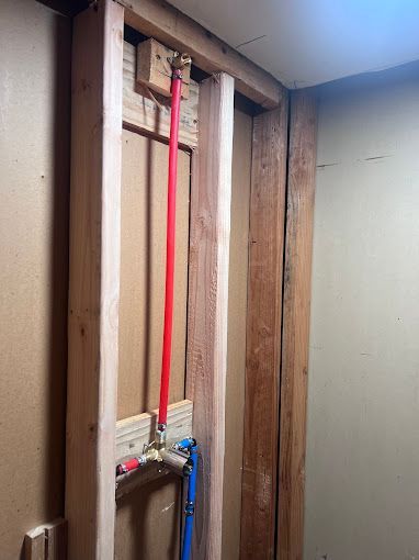 A bathroom with a wooden frame and pipes coming out of it.