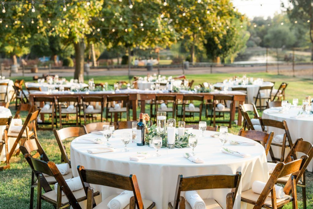 Outdoor wedding reception with round tables, brown chairs, and festive decorations.