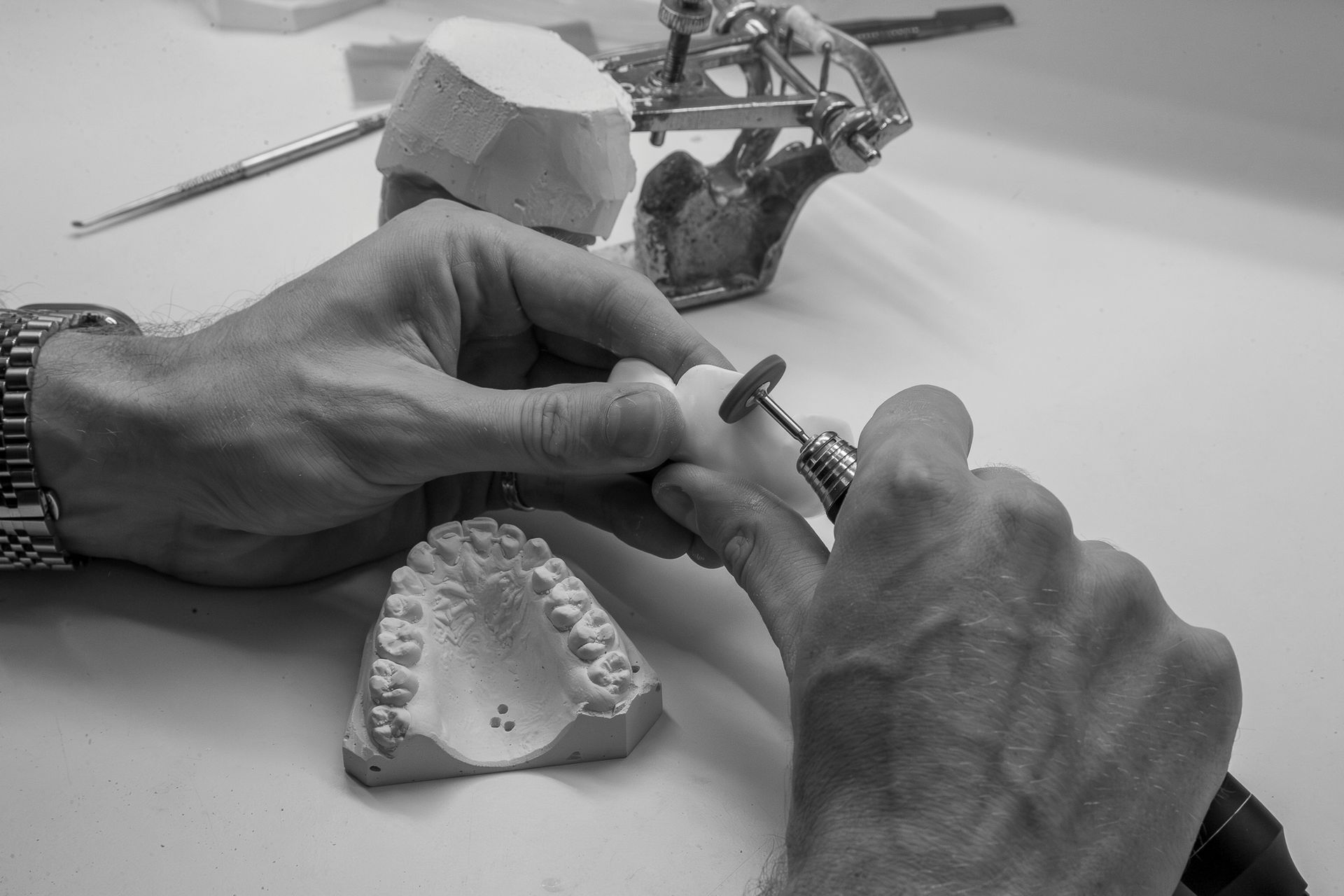 Hands Shaping a Dental Mold With Tools on a Workbench — Smiles On Hobart in Hobart, TAS