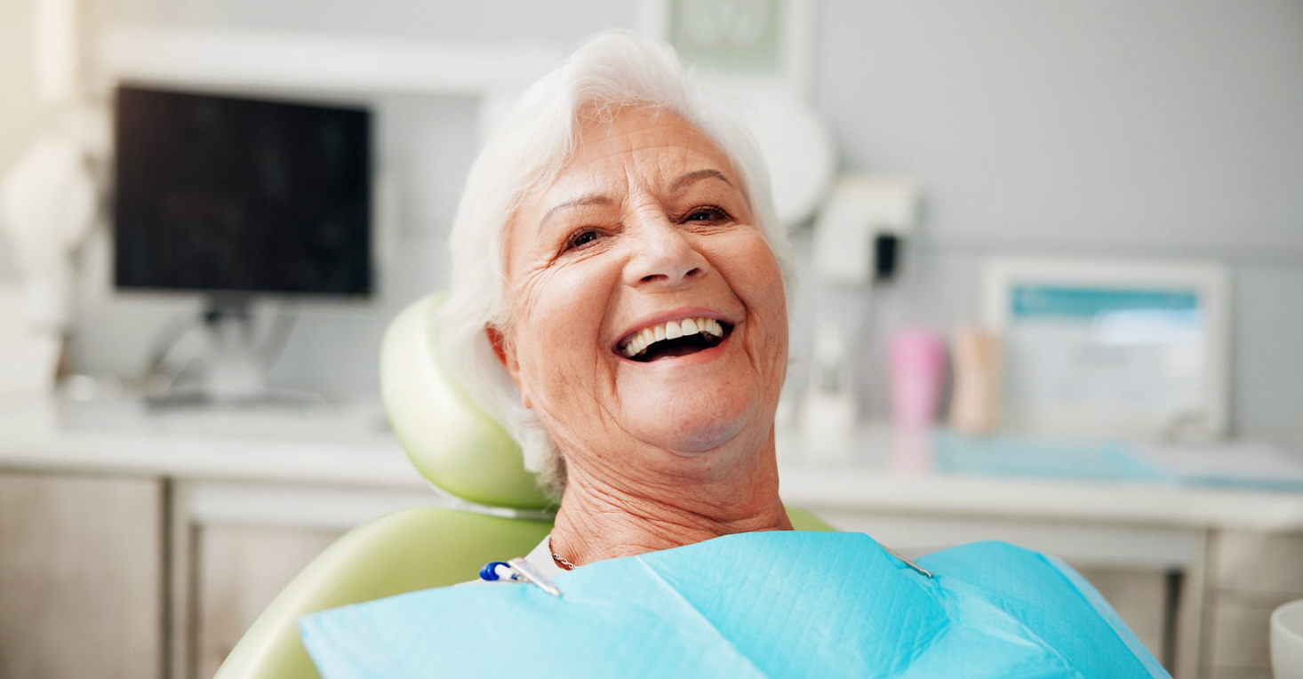 Smiling Person in a Dental Chair With Blue Bib in a Bright Clinic — Smiles On Hobart in Hobart, TAS