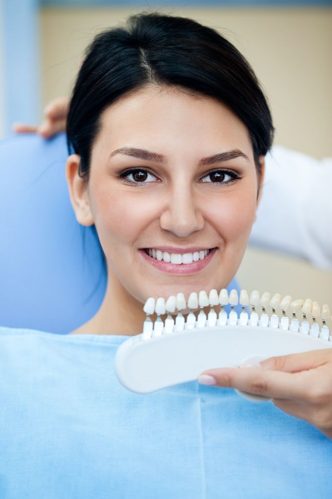 Smiling Dental Patient Holding a Shade Guide During a Teeth Whitening Consultation — Smiles On Hobart in Sorell, TAS