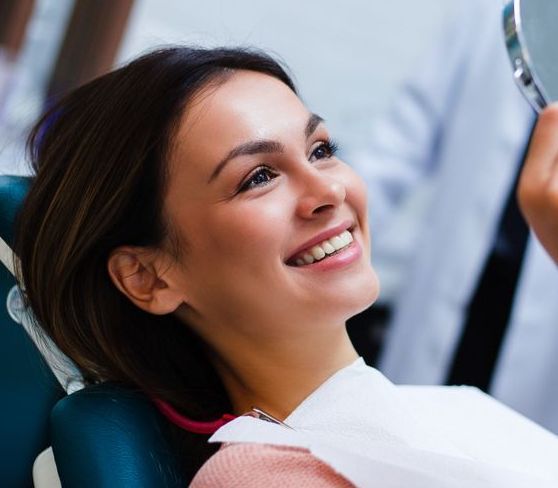 Smiling Patient Reclining in a Dental Chair While a Dentist Examines Her Teeth — Smiles On Hobart in Hobart, TAS