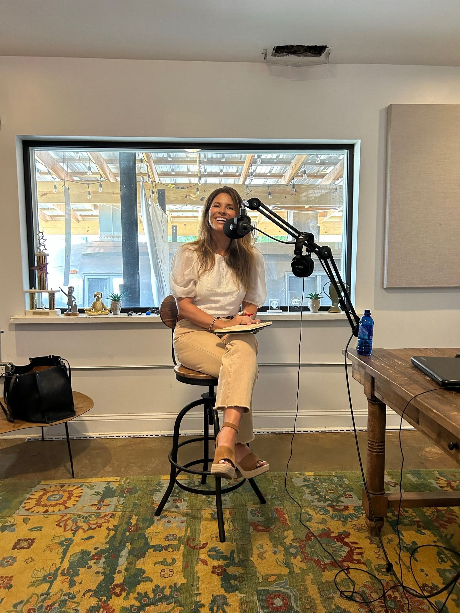 Woman seated on a stool speaking into a microphone in a bright studio space