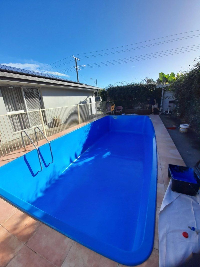 Backyard swimming pool being lined with bright blue material next to a house and patio area