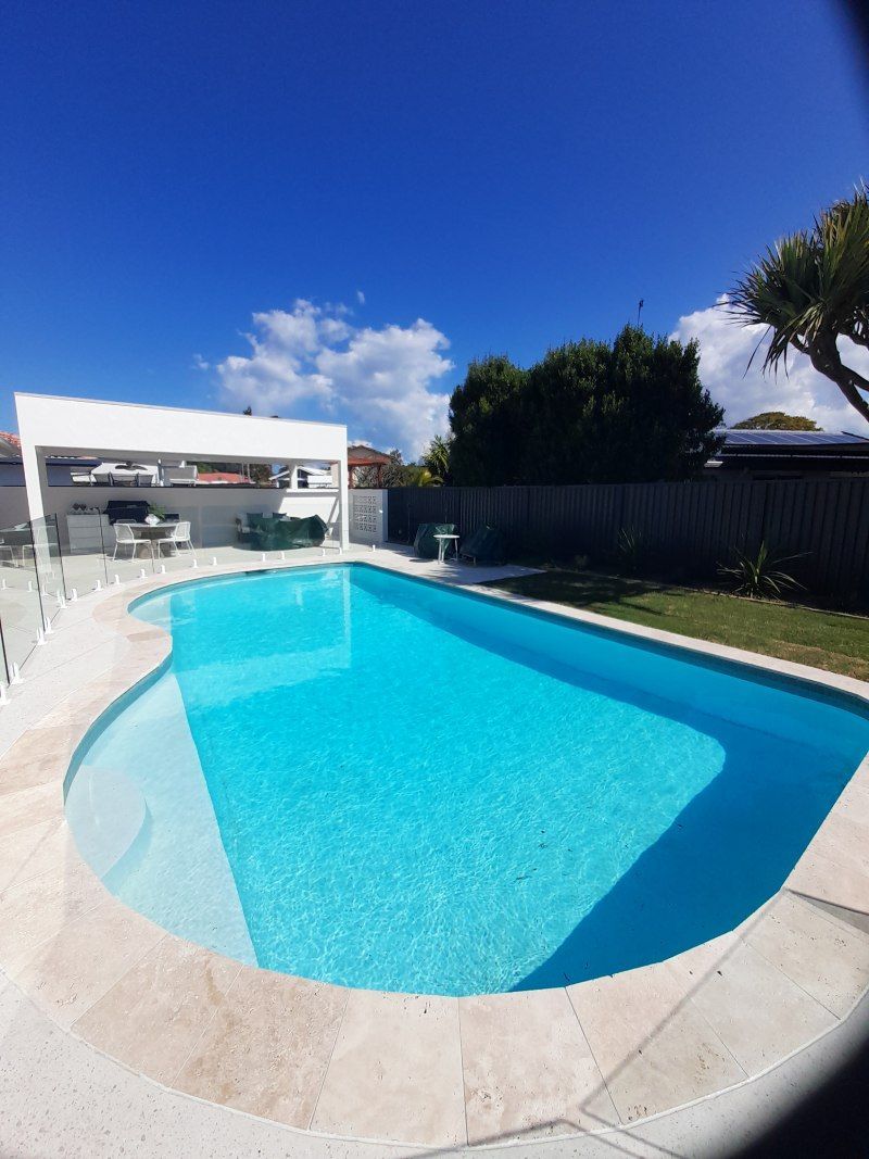 Backyard swimming pool with blue water, white deck, and a clear sunny sky