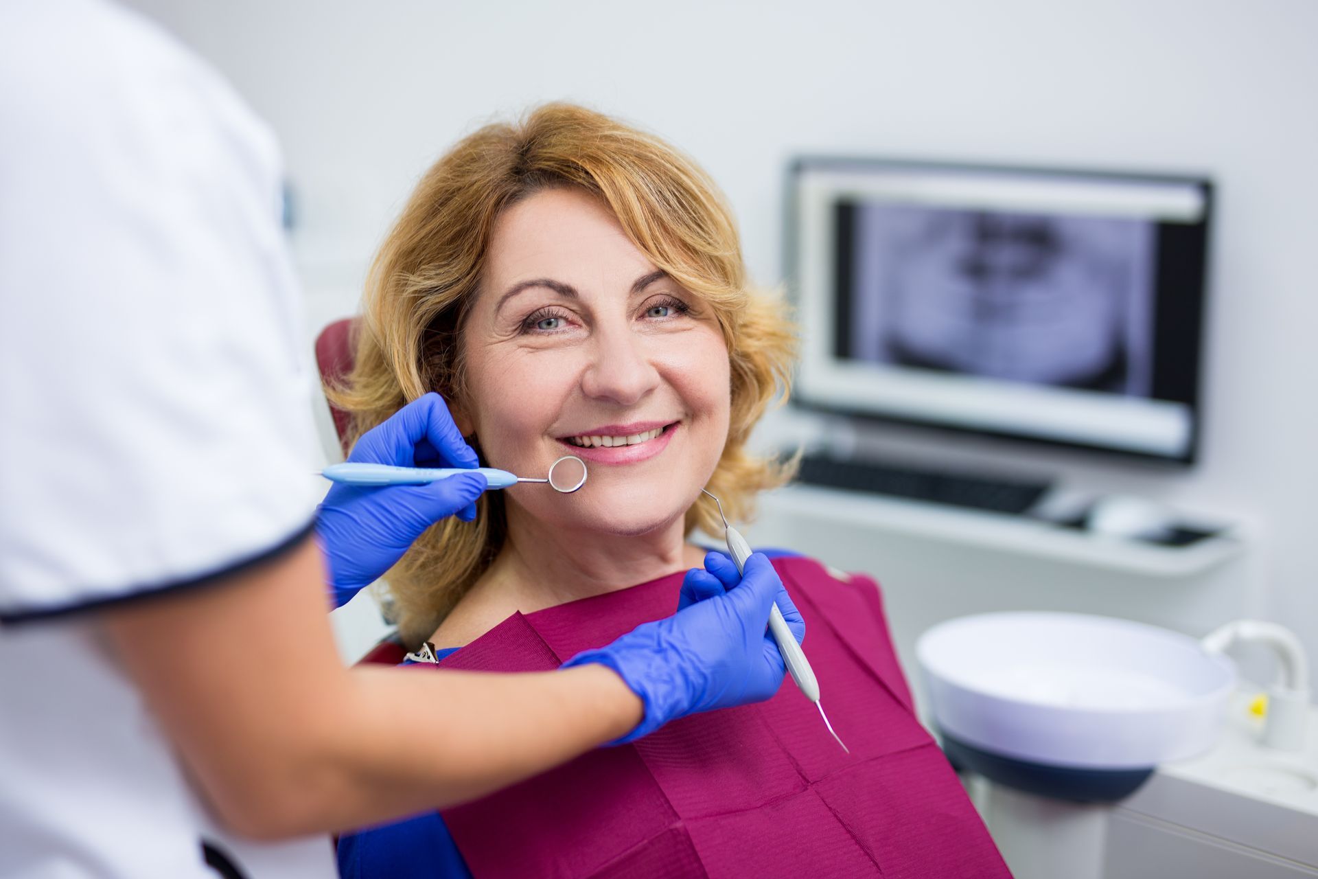 Dentist pointing to equipment, showing a patient. Blue drape and mask. Schedule an Appointment! text. Dentist pointing to equipment, showing a patient. Blue drape and mask. Schedule an Appointment! text.