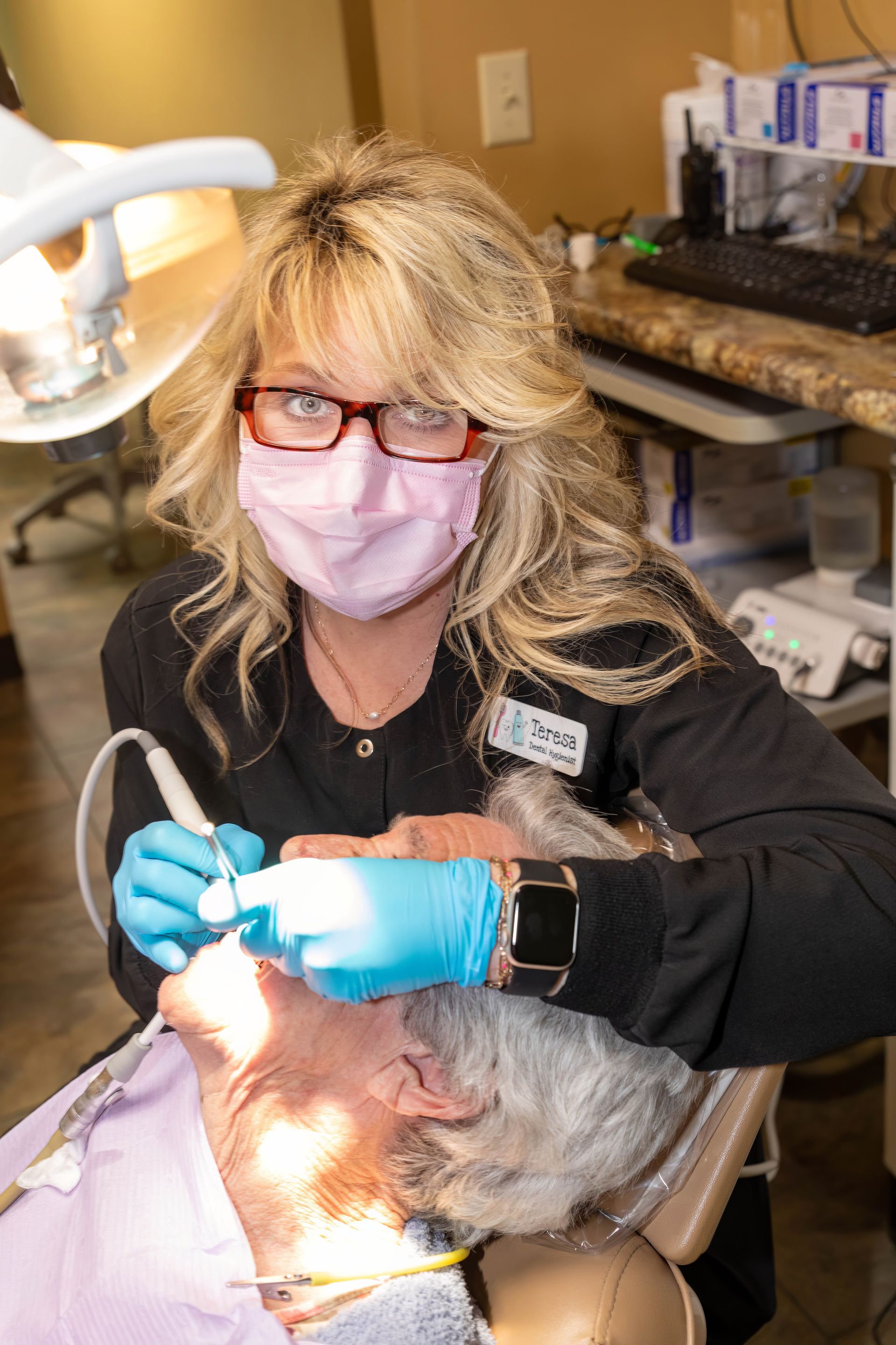 Dentist in mask and gloves examining a patient's teeth with dental tools in an office setting. Dentist in mask and gloves examining a patient's teeth with dental tools in an office setting.