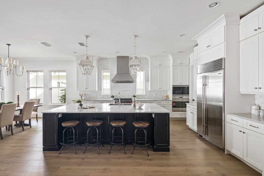 A kitchen with white cabinets and stainless steel appliances and a large island.