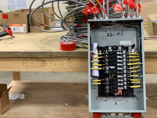 Open electrical control panel with labeled wiring and connectors on a workbench