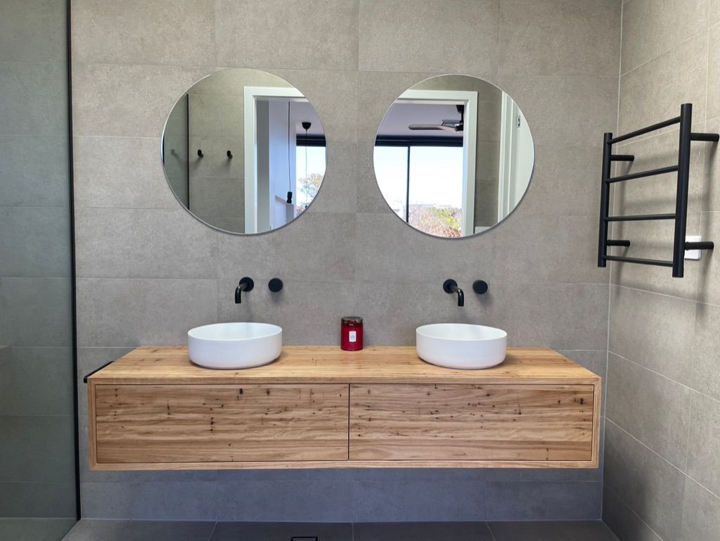 Bathroom with wooden vanity, two round mirrors, and black fixtures. — All Stars Plumbing In Shellharbour, NSW