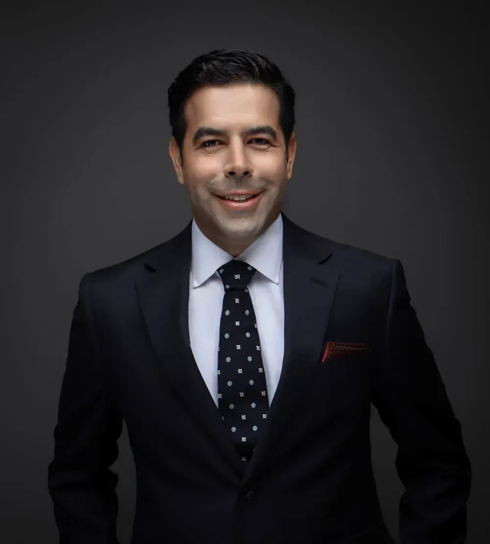 A man in a suit and tie is smiling for the camera