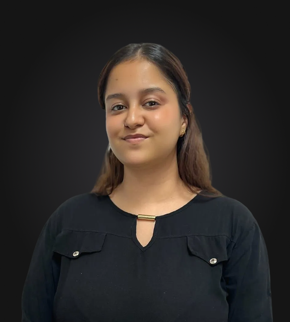 A woman wearing a black shirt and a watch is standing in front of a black background.