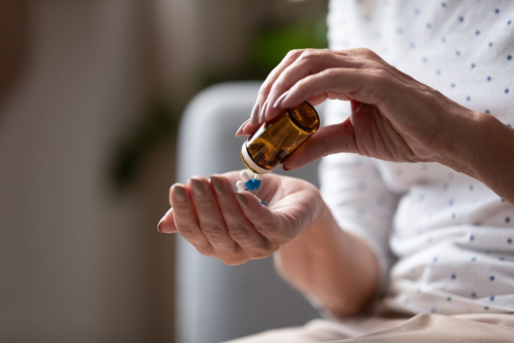 Person pouring liquid medicine into an outstretched palm from a brown bottle
