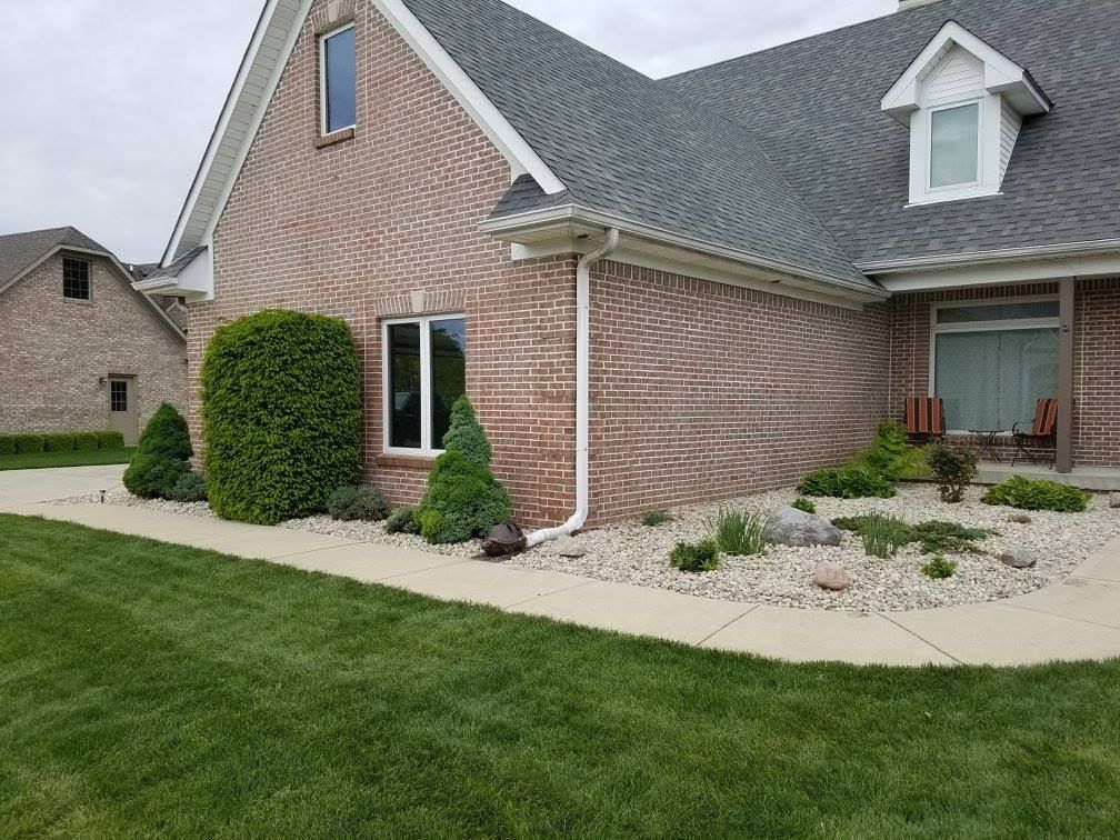 A brick house with a gray roof and a walkway in front of it.