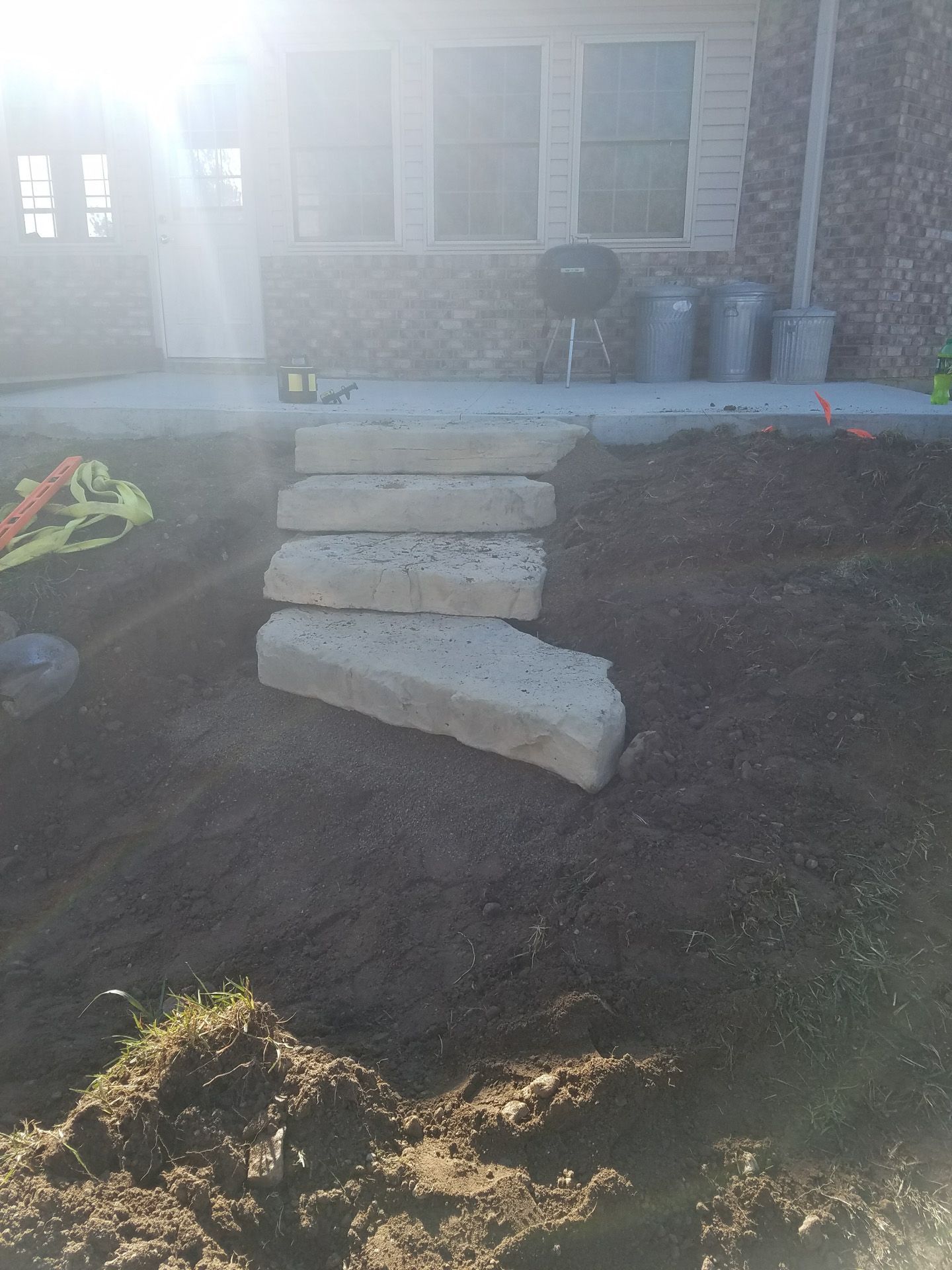 A stack of concrete blocks sitting on top of a pile of dirt in front of a house.