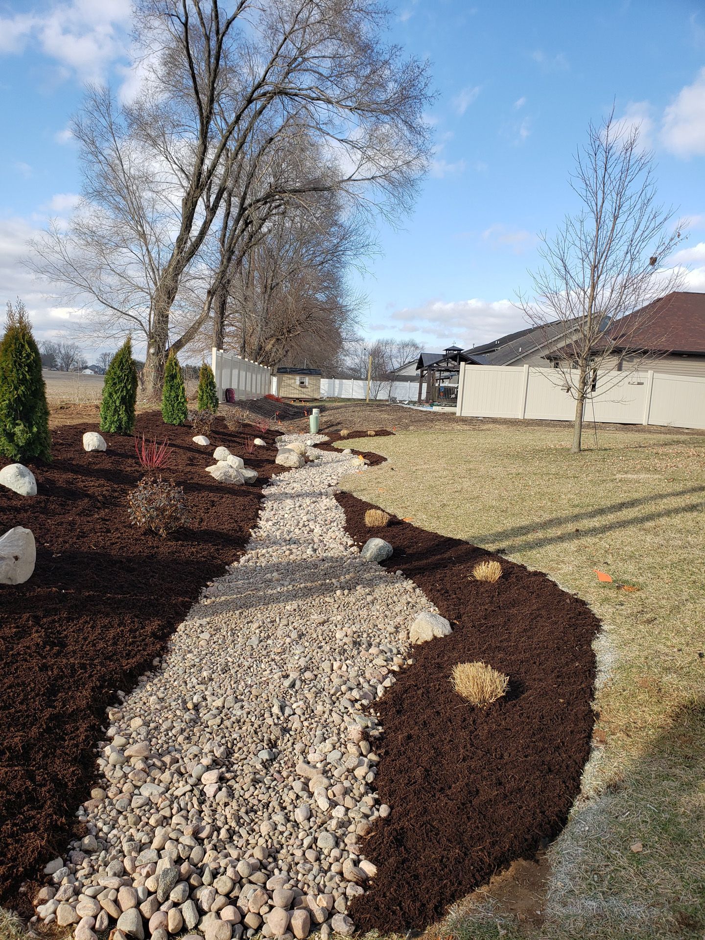 There is a path in the middle of the yard with rocks and mulch.
