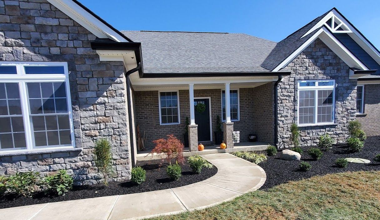 A brick house with a gray roof and a walkway leading to it.