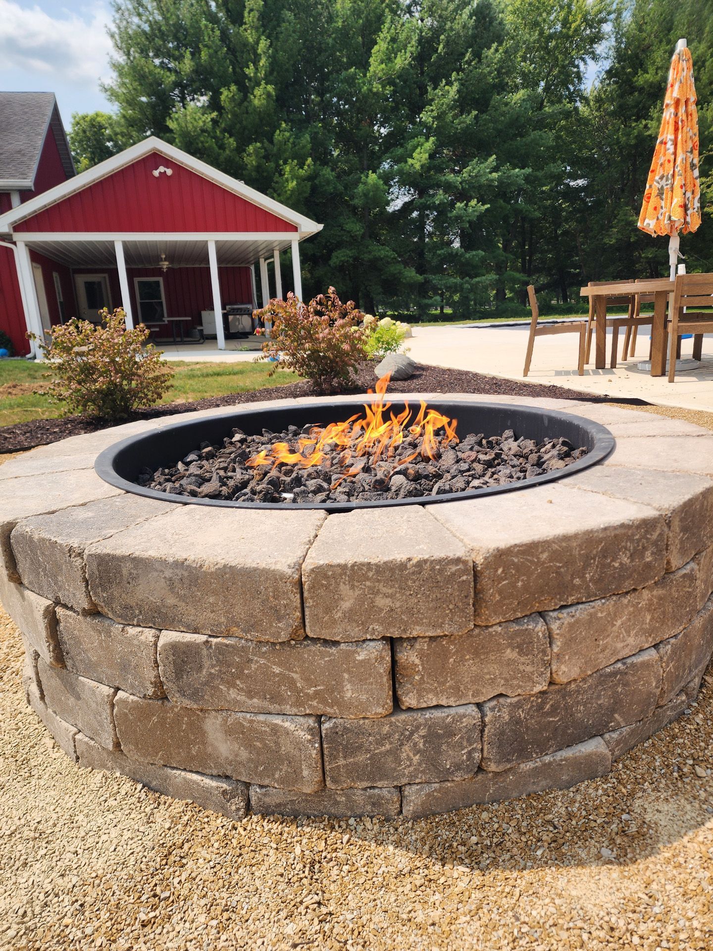A fire pit is sitting in front of a red house.