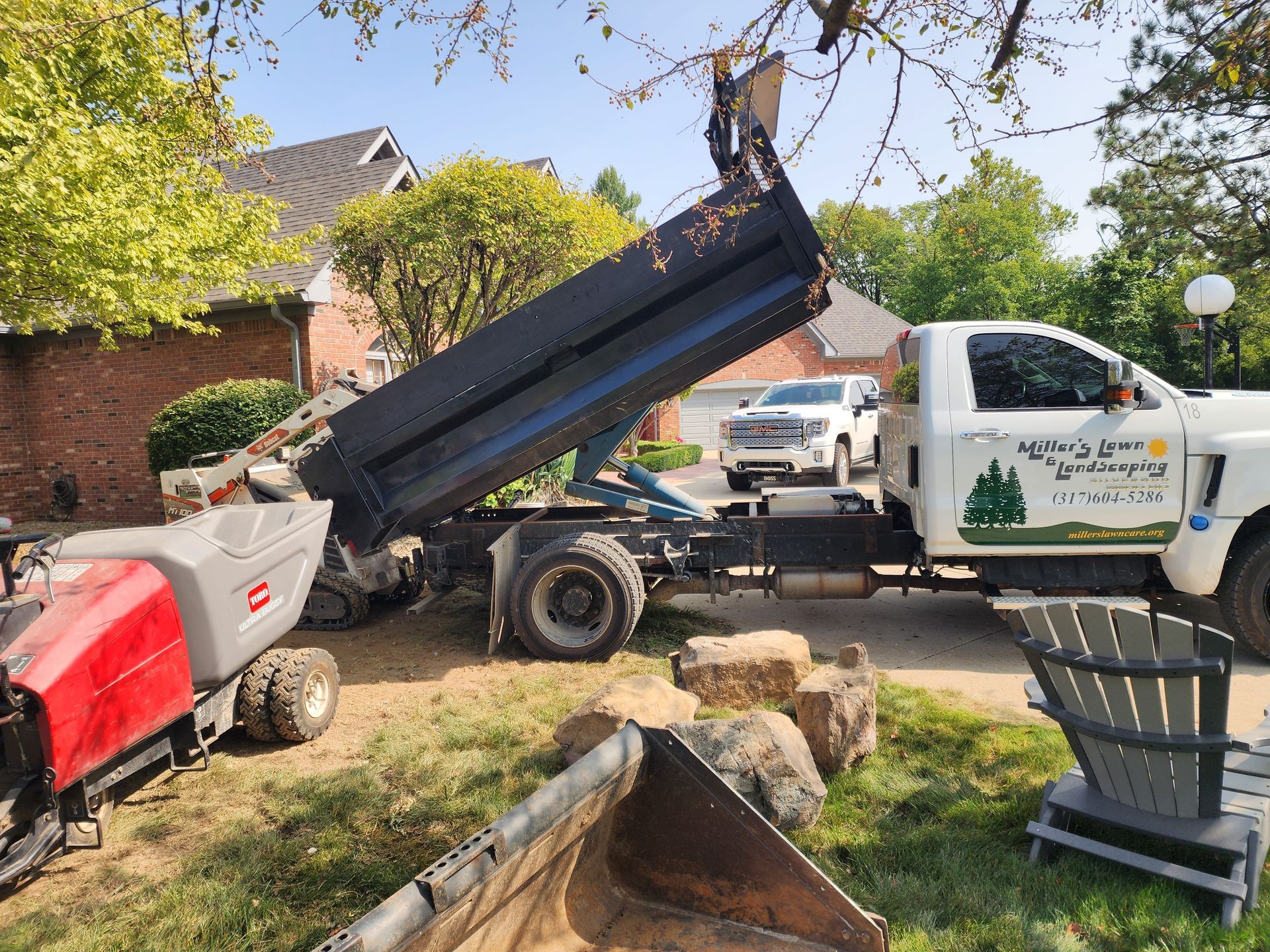 A dump truck is being loaded with dirt in a yard.