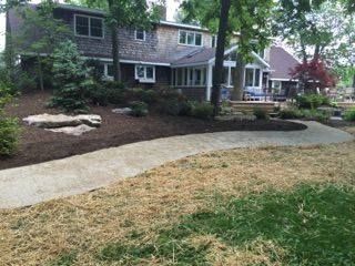 A house with a walkway leading to it and a lawn in front of it.