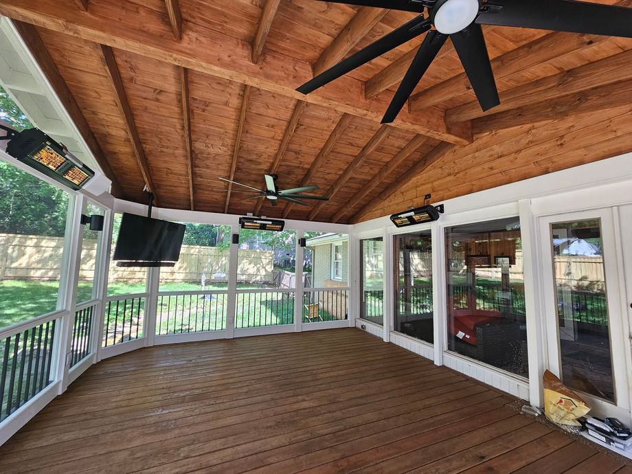 Covered wooden porch with white railings, ceiling fan, and sliding glass doors overlooking a yard