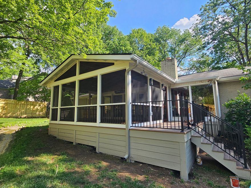 Screened porch with pale yellow trim and white lattice on a sunny, tree-lined house exterior